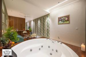 een groot wit bad in een badkamer met een kaars bij The BlackPearl Hillcrest in Kasauli +126 foto's