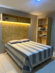 a bedroom with a bed with a blue and white striped blanket at Flat Lagoa Seca in Juazeiro do Norte
