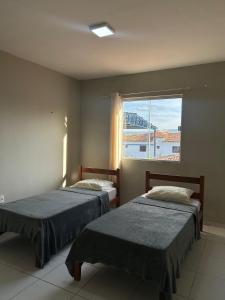 two beds in a room with a window at Flat Lagoa Seca in Juazeiro do Norte