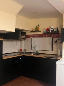 a kitchen with black cabinets and a sink at El rincón de Bonilla in El Ronquillo