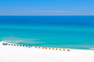 a line of chairs on a beach next to the ocean at Sunny and Share in Destin