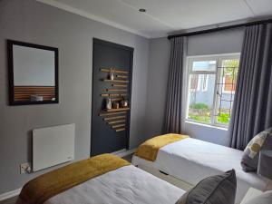 a hotel room with two beds and a window at Roux Casa in Swellendam