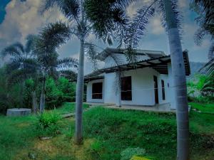 a white house with palm trees in front of it at Adithya Resort in Nikawatawana