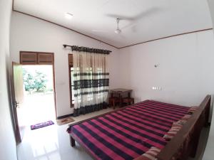 a bedroom with a bed with a striped blanket at Adithya Resort in Nikawatawana +11 photos