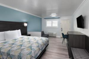 Un dormitorio con cama, escritorio y televisión. en Red Lion Inn & Suites Lemoore, en Lemoore