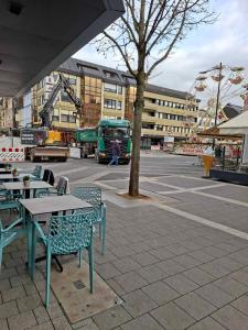 eine Außenterrasse mit Tischen und Stühlen und einem LKW in der Unterkunft Citystudio Neuwied mit Schlafgalerie bis 5 Gäste direkt am Luisenplatz in Neuwied