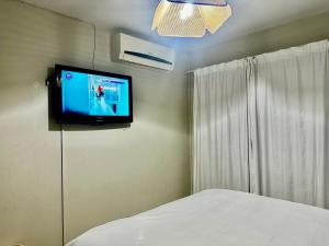 una camera da letto con una tv a parete e un letto di Feel At Home Cosy Apartment a Gaborone