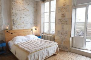 a bedroom with a bed and a large window at Hôtel Le Sénéchal in Ars-en-Ré