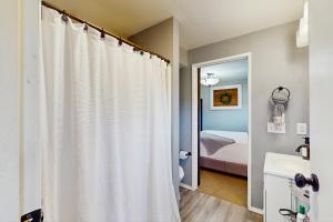 Un baño con una cortina de ducha blanca y una cama. en Scandia Suite, en Keyport