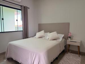 a white bedroom with a bed and a window at Apartamento com Varanda e Ar Condicionado in Sinop