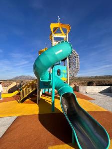 a playground with a blue slide on top of it at Las cuevas de María in Bácor +16 photos