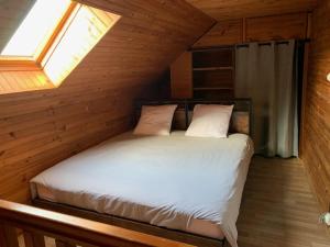 een bed in een houten kamer met een raam bij A l'orée des bois in Lyons-la-Forêt