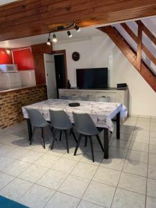 een keuken met een tafel met stoelen en een televisie bij A l'orée des bois in Lyons-la-Forêt