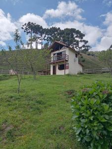 ein Haus auf einem Hügel mit einer Wiese in der Unterkunft Sítio Araucária in Itamonte