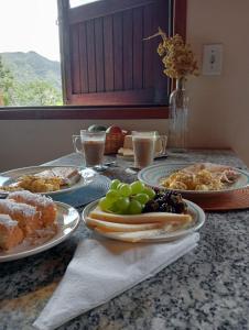 ein Tisch mit Tellern voller Essen auf einem Tisch in der Unterkunft Sítio Araucária in Itamonte