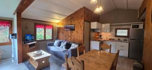 a kitchen and a living room with a couch and a table at Chalet du Feignole in Gerbépal