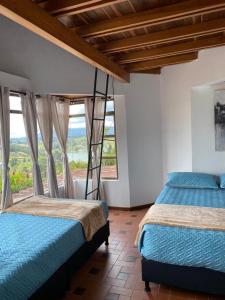 El PeñolにあるRocks Glamping - Guatapé, El Peñolのベッドが2つと大きな窓がある寝室