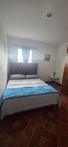 a bedroom with a bed with a blue comforter and a window at Aparto hotel del centro in Filandia