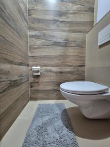 a bathroom with a toilet and a wooden wall at Apartmán LUX Lučenec in Lučenec