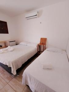 a room with two beds and a chair at Pousada Villa Zarah in São Miguel do Gostoso