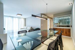 a dining room with a glass table and chairs at Boulevard 308B - Excelente cobertura em condomínio de luxo no centro de Bombinhas - Piscina - Jacuzzi - Academia - Portaria 24h - (Consultar serviços de roupa de cama e banho) in Bombinhas