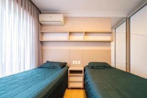 a bedroom with two beds and a desk and a window at Boulevard 308B - Excelente cobertura em condomínio de luxo no centro de Bombinhas - Piscina - Jacuzzi - Academia - Portaria 24h - (Consultar serviços de roupa de cama e banho) in Bombinhas +60 photos