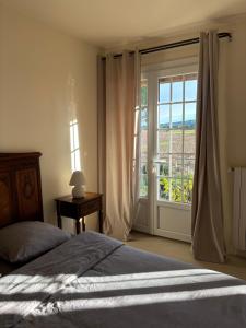 Un dormitorio con una cama y una ventana grande. en Le Mas des Vignes en Drome provençale, en Rochegude