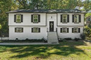 une maison blanche avec des fenêtres noires et une porte dans l'établissement Stylish 4BR Getaway with Game Room, Grills & Cozy Outdoor Fire-Pit, à Cary