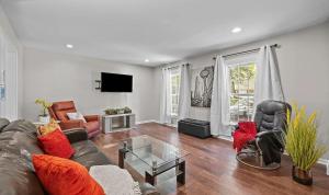 un salon avec un canapé, des chaises et une télévision dans l'établissement Stylish 4BR Getaway with Game Room, Grills & Cozy Outdoor Fire-Pit, à Cary