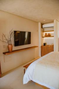 Un dormitorio con un televisor de pantalla plana en la pared. en Lahaina Hotel, en Amontada