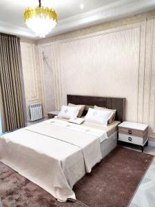 a bedroom with a large white bed with a chandelier at Tashkent City Apartments D11 in Tashkent +13 photos