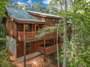 a wooden cabin in the woods with a balcony at Luxury Cabin • 4 King Beds • Jacuzzi in Each Room in Cartertown