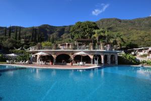 a resort with a large swimming pool with mountains in the background at Mama Chuy Hotel & Villas Ajijic in San Juan Cosalá
