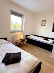 a bedroom with two beds and a window and a table at Pension Bockenem Extra in Bockenem +5 photos