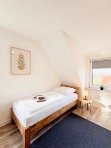 a white bedroom with a bed and a window at Pension Bockenem Extra in Bockenem