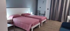 two beds in a hotel room with pink covers at Montecarlo B&B in Tortona +4 photos