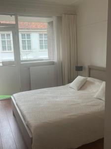 a white bed in a bedroom with a window at Franciscus in Bergen op Zoom