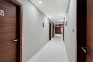 a hallway with white floors and wooden doors at Collection O Motipura Bus Terminal Formerly Hotel Navjivan in Himatnagar