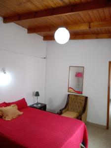 een slaapkamer met een rood bed en een stoel bij Depto cómodo y confortable in Olavarría