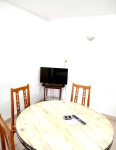 een houten tafel met stoelen en een televisie in een kamer bij Depto cómodo y confortable in Olavarría