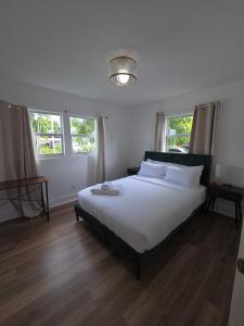 西棕榈滩Cozy 3BR WPB Cottage的卧室里有一张床，铺着白色的床单，还有窗户