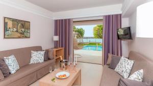a living room with a couch and a tv at Porto Platanias Beach Resort & Spa in Plataniás