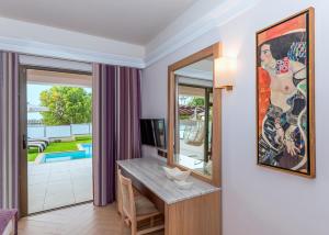 a living room with a table and a mirror at Porto Platanias Beach Resort & Spa in Plataniás
