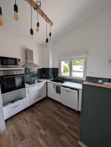 una grande cucina con banconi bianchi e una finestra di Gite de campagne avec SPA privatif a Saint-Sauvant