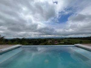 a large blue swimming pool with a cloudy sky at New Espectacular Chalet de lujo con vistas de lujo in Quindío
