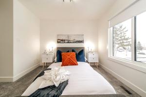 a white bedroom with a large bed with an orange pillow at 5BDRM Chic Modern Home-Hot Tub-King Bed-AC-Garage in Edmonton +105 photos