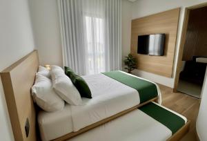 1 dormitorio con 1 cama con almohadas y TV en Acqua Di Mare Pousada, en Itanhaém