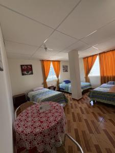 a room with three beds and orange curtains at Hostal Shaddai in Manta