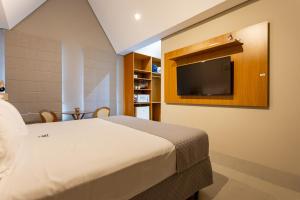 a bedroom with a bed and a flat screen tv at Vilinha típica - Suíte Onze Tuin - Entrada com senha - Somos hospedagem por temporada in Holambra