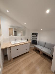 bagno con lavandino, divano e specchio di Gite de campagne avec SPA privatif a Saint-Sauvant